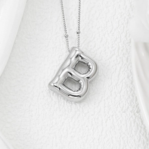 Macro shot of 3D puffed letter B silver pendant with shiny polished metal surface