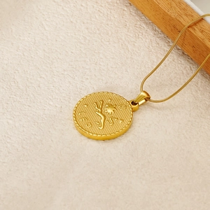 Close-up of gold Leo zodiac coin pendant with engraved lion motif on white fabric