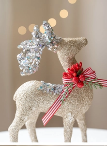 Close-up of glittery Christmas reindeer ornament with red berries and festive ribbon details