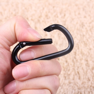 Heavy duty black D-ring carabiner clip with spring gate shown in hand for outdoor use