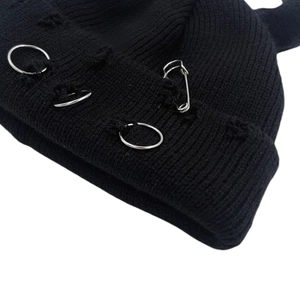Distressed black knit beanie with silver rings and safety pin in punk style