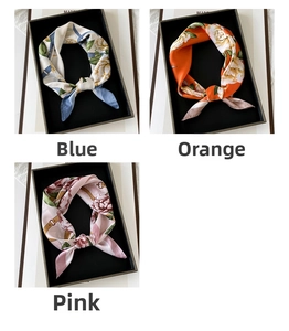 Detailed view of floral satin scarves in blue orange and pink gift box presentation