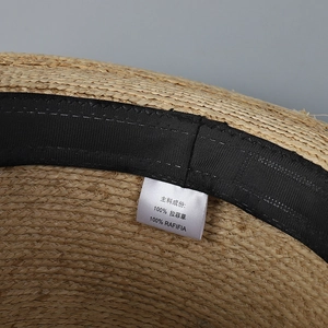 Detail of 100% natural raffia straw hat with internal black sweatband and material label
