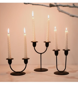 Three elegant black double-headed metal candle holders with white spiral tapered candles