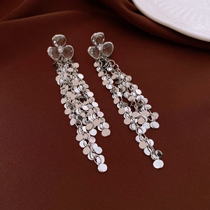 Detailed view of silver flower earrings with long shimmering metallic tassel chains