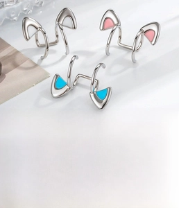Close-up of minimalist titanium steel cat ear clips in white, pink and blue enamel