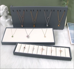 Three-piece jewelry display set with gray necklace stand and ring tray on white faux fur