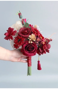 Detail of red silk roses with golden fans and tassels for Chinese wedding bouquet