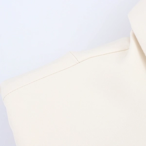 Detailed macro shot showing the beige woven fabric texture and lapel shoulder stitching