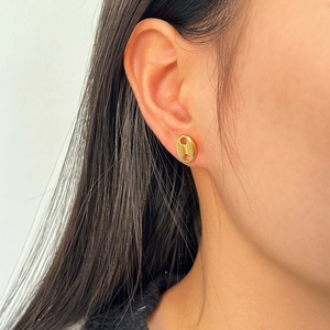 Close-up of golden coffee bean stud earrings with polished finish on a model's ear