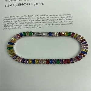 Close-up of multicolor rectangular gemstones on a silver tennis bracelet over a magazine