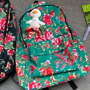 Detailed top view of a colorful floral backpack with a cute plush duck charm and stationery