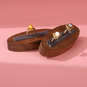 Minimalist walnut ring display stands with gold pearl rings on a pink background