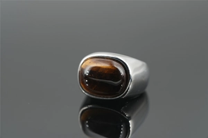 Macro shot of polished stainless steel ring with large oval brown tiger eye stone