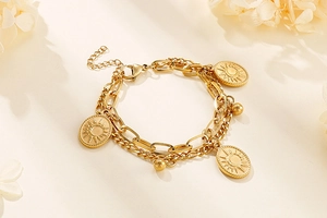 Detail of layered gold sun pendant bracelet with beads on a minimalist warm background