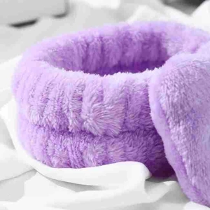 Soft purple coral fleece headband for makeup shown on a textured white fabric background