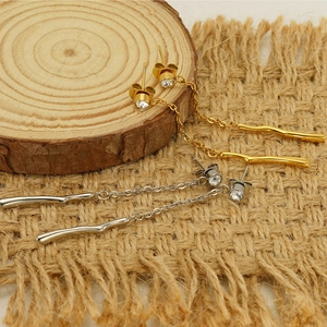 Detailed view of gold and silver tassel earrings with zircon studs on rustic wood