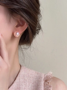 Close-up of pink metallic ball stud earring on ear showing smooth mirror-like finish