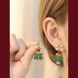 Handmade beaded Christmas tree earrings with gold bows and red beads on ear
