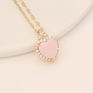 Close-up of gold heart necklace with pink gemstone and clear zirconia accents