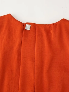 Detail of satin dress back neckline featuring a square metal button and pleated fabric