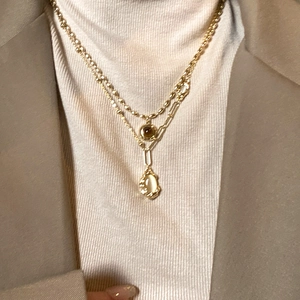 Detail of double-layer bamboo joint necklace with oval gemstone on a white sweater