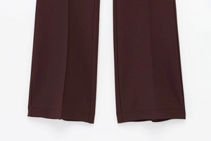 Détail de l'ourlet de pantalon bordeaux avec un tissage textile texturé précis