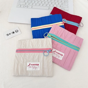Flat lay of small pleated fabric pouches in beige, pink, blue, and burgundy colors