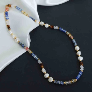 Macro detail of Bohemian beaded necklace with blue stones and freshwater pearls on silk