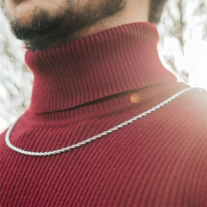 Close-up of a silver rope chain necklace worn by a model in soft natural sunlight