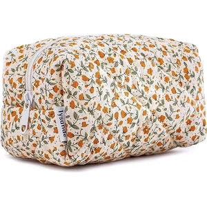 Detailed view of quilted cotton makeup bag with orange floral patterns and white zipper