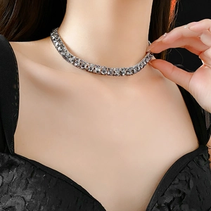 Silver choker necklace with square rhinestones worn by model on black background