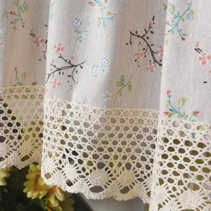 Detailed macro view of beige floral linen curtain with intricate crochet lace trim finish