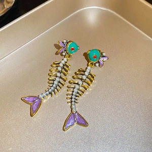 Detailed close-up of fishbone earrings featuring green enamel and small white pearls