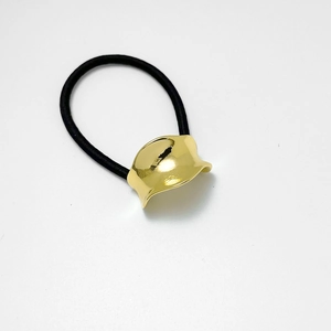 Dettaglio macro di elastico per capelli nero con inserto in metallo dorato concavo