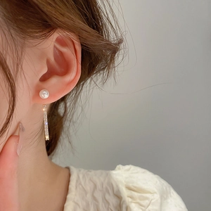 Close-up of gold-plated tassel earrings featuring white pearls and micro-pave zircons