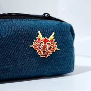 Traditional Chinese dragon enamel brooch in red and gold on denim fabric