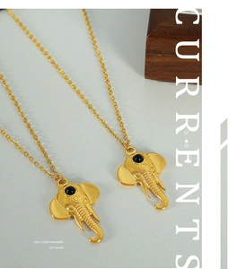 Detailed view of gold elephant head pendant with black gemstone eye on elegant backdrop