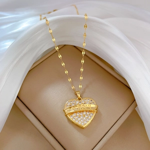 Golden heart necklace with sparkling zircon stones and MAMA charm on white silk background