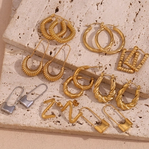 Detailed flat lay of geometric gold and silver stainless steel earrings on marble