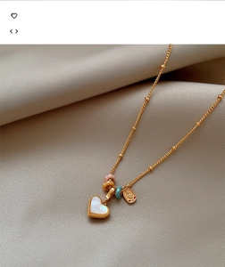 Detail of 18k gold heart pendant necklace with mother of pearl and mini colorful beads