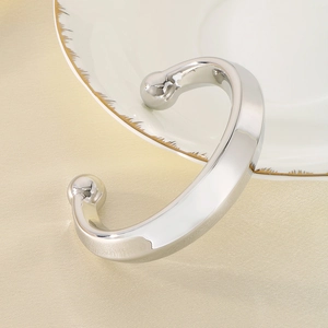 Détail macro du bracelet jonc argenté minimaliste en forme de C avec boules aux extrémités
