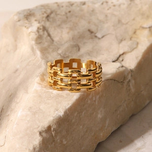 18K gold plated mesh watch strap style ring for women on a beige textured stone
