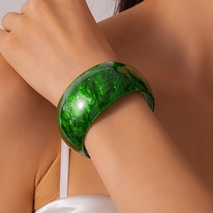 Close-up of green marble acrylic cuff bracelet on model with white silk garment