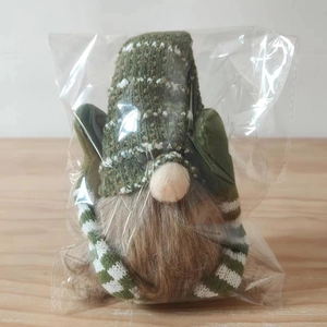 Detail of a Christmas gnome plush with a green knitted hat and long brown beard in packaging