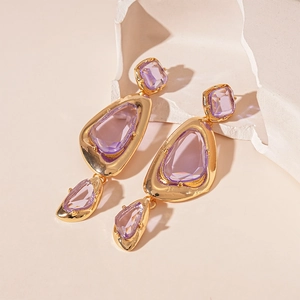 Detailed view of vintage gold-tone earrings with purple crystals on beige background