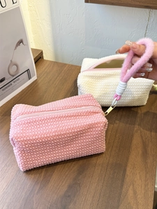 Detail of plush makeup bags in pink and cream with soft textured fabric and gold zippers