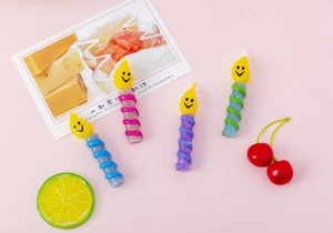 Close-up of spiral birthday candles in pastel colors with cute yellow smiley face toppers