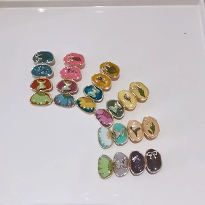 Detailed top view of DIY jewelry charms with colorful floral and butterfly patterns