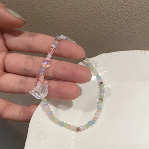 Detail of colorful faceted beads and a large iridescent butterfly charm on a bracelet